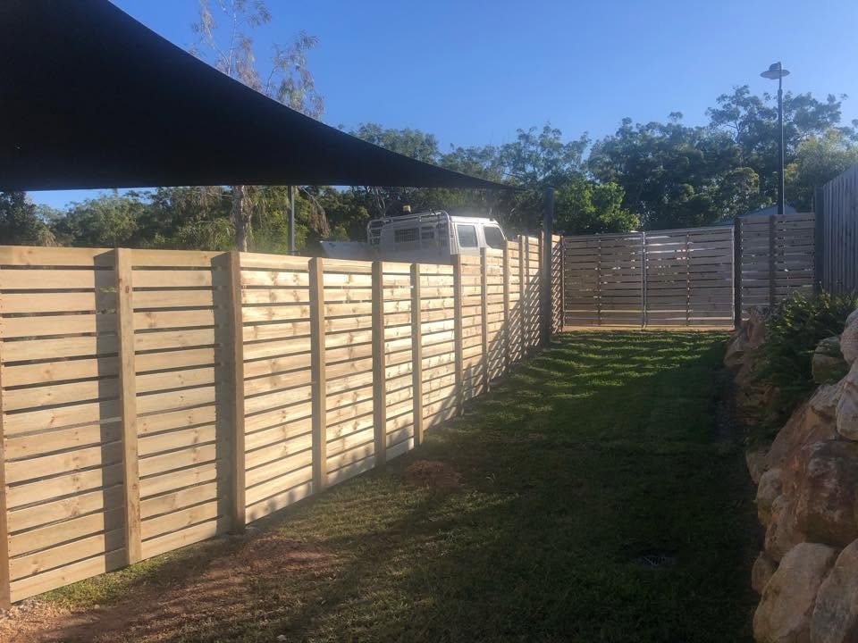 Finished horizontal slat timber fence with sandstone retaining wall in a Redlands backyard